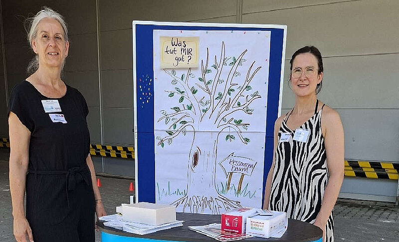 Zwei Mitarbeitende der Fachstelle Sucht vor einem Stand der Regionalen Diakonie Westerwald Rhein-Lahn.
