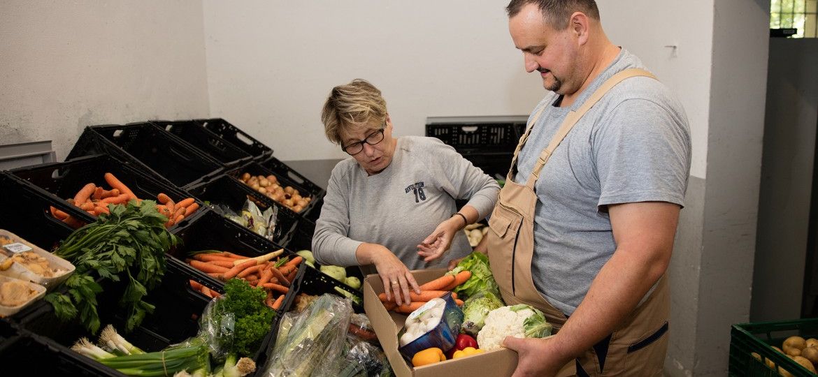 Tafelarbeit - Zwei Personen packen eine Kiste mit Gemüse