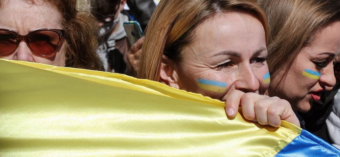 Demonstanten mit ukrainischer Flagge in der hand und auf die Wangen gemalt