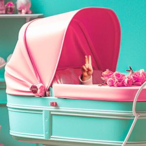 KI-generiertes Bild: Ein Baby liegt in einem türkis und rosafarbenen Kinderwagen. Umgeben von Blumen, Geschenken und Spielsachen ebenfalls in rosa und türkis. Vom Baby ist nur die Hand aus dem Kinderwagen zu sehen, die das Peace-Zeichen zeigt.